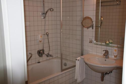 y baño con bañera, lavamanos y ducha. en Hotel Vierseithof Luckenwalde, en Luckenwalde