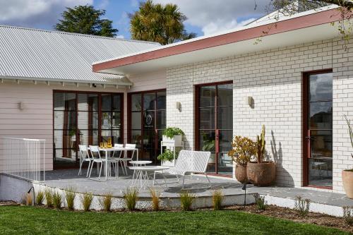 a house with a table and chairs on a patio at Months and Seasons Design-led Country House in Daylesford