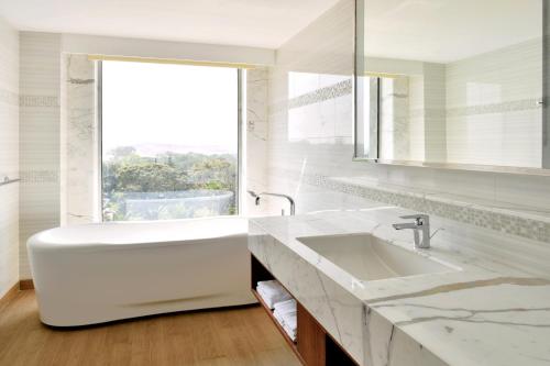 a white bathroom with a tub and a window at Fairfield by Marriott Belagavi in Belgaum