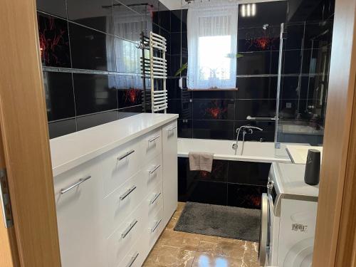 a black tiled bathroom with a sink and a tub at Zajazd u Piasta Kołodzieja in Kruszwica