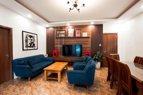 sala de estar con sillas azules, mesa y TV en AK Homestay - Motorbike Rental - Cao Bang City, en Cao Bằng