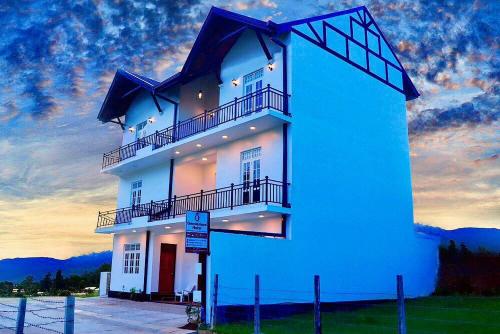 a large white building with a sunset in the background at Queensland Hotel in Nuwara Eliya