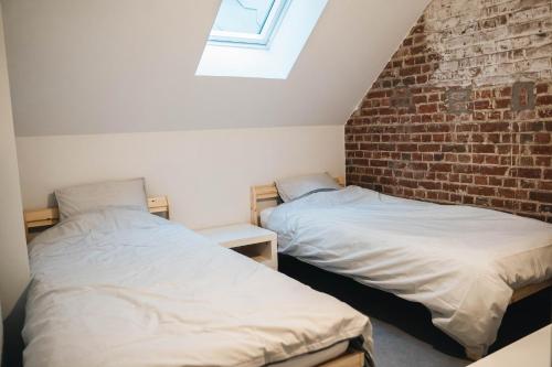 2 camas en una habitación con una pared de ladrillo en Gezellige loft met twee slaapkamers, en Ypres