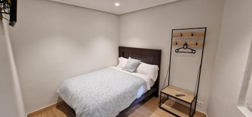 Dormitorio pequeño con cama y espejo en El Cuarto del Marqués - Sin ascensor pegado a playa San Lorenzo, en Gijón