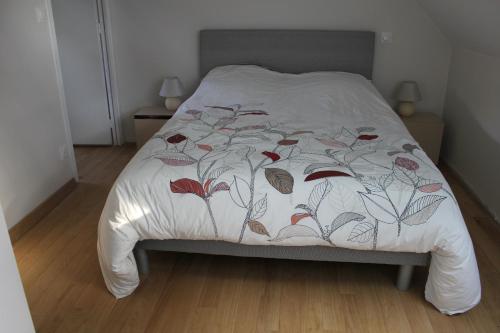 ein Bett mit einer weißen Decke mit Blättern darauf in der Unterkunft La Pérenne in Pénestin