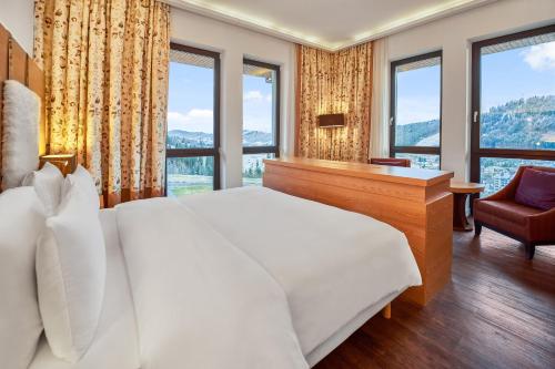 a bedroom with a large bed and a desk and windows at Radisson Blu Resort Bukovel in Bukovel