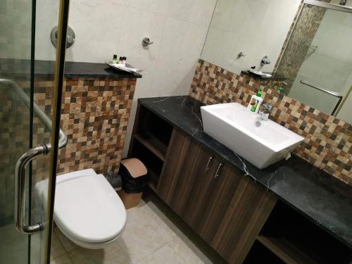 een badkamer met een wastafel, een toilet en een spiegel bij Luxury 3BhK Service Apartment Manyata tech Park Hebbal in Bangalore