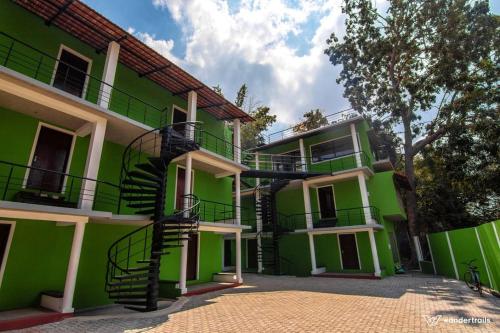 un bâtiment vert avec un escalier en colimaçon devant lui dans l'établissement Paradise Le Tamarin, à Auroville