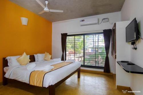 a bedroom with a bed with a television and a window at Paradise Le Tamarin in Auroville
