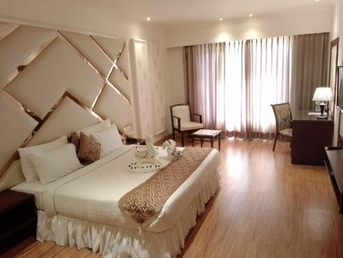 um quarto de hotel com uma cama grande e uma sala de estar em The Stella Hotel & Resort em Ludhiana