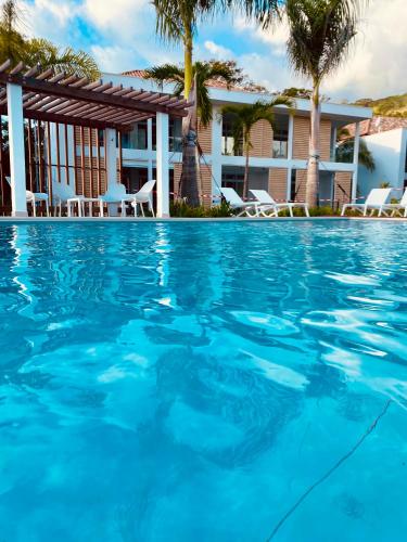 a swimming pool in front of a house with palm trees at Villa TE URA Beach in Paea
