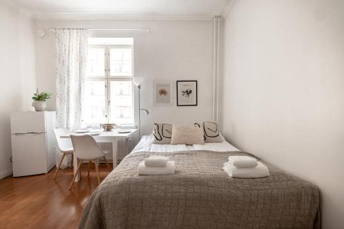 a white bedroom with a bed and a table and a window at 2ndhomes Cozy and Compact studio in Kamppi in Helsinki