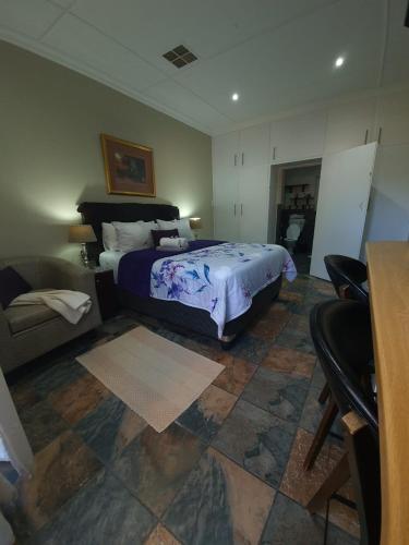 a bedroom with a bed and a couch and a table at Tehillah Guesthouse in Upington
