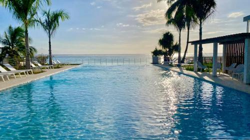 a swimming pool next to the ocean with palm trees at Villa TE URA Beach in Paea