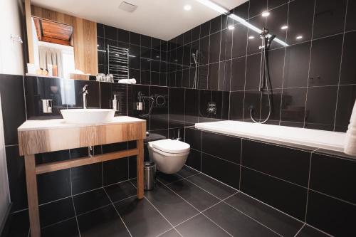 a bathroom with a sink and a toilet and a tub at Hotel ALBRECHT in Bratislava