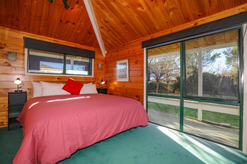 a bedroom with a bed and a large window at Five Mile Yay - Five Mile Bay Holiday Home in Taupo