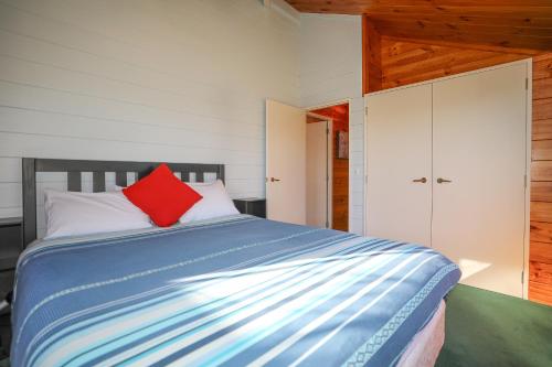 a bedroom with a bed with a red pillow on it at Five Mile Yay - Five Mile Bay Holiday Home in Taupo