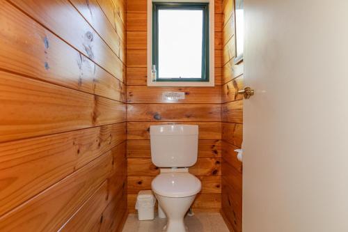 a bathroom with a toilet and wooden walls at Five Mile Yay - Five Mile Bay Holiday Home in Taupo