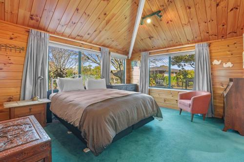 Schlafzimmer mit einem Bett, einem Stuhl und Fenstern in der Unterkunft Five Mile Yay - Five Mile Bay Holiday Home in Taupo