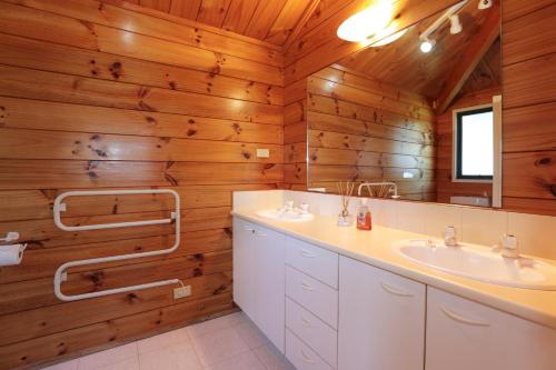 ein Badezimmer mit 2 Waschbecken, einem Spiegel und Holzwänden in der Unterkunft Five Mile Yay - Five Mile Bay Holiday Home in Taupo