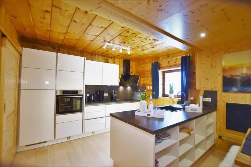 a kitchen with white cabinets and a black counter top at Zirbenwald Lodge in Turracher Hohe