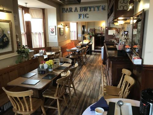 un restaurante con mesas y sillas de madera y un bar en The Victoria Hotel, en Pwllheli