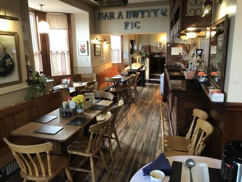 Un restaurante con mesas y sillas de madera y un bar. en The Victoria Hotel, en Pwllheli