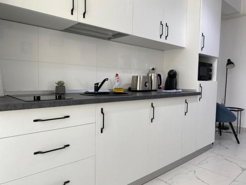 cocina con armarios blancos y encimera en Lazar Towers Studios & Apartments near Palas, en Iaşi