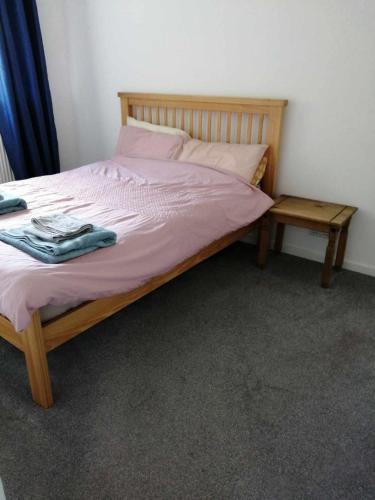 een bed met een houten frame en een nachtkastje bij Beacons view in Hirwaun