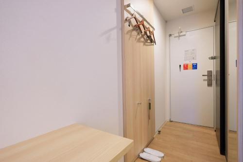 a room with a hallway with a door and a table at Park Central Sakura Hotel in Osaka