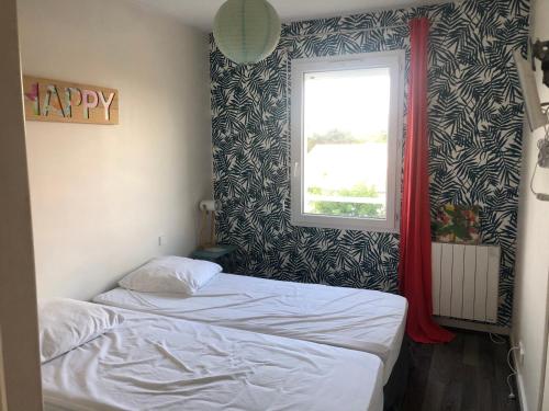 une petite chambre avec un lit et une fenêtre dans l'établissement T2 avec piscine et terrasse dans résidence arborée, à La Rochelle