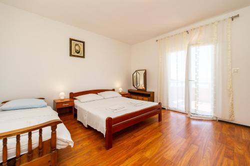1 dormitorio con 2 camas y ventana grande en Apartments Zora en Lun
