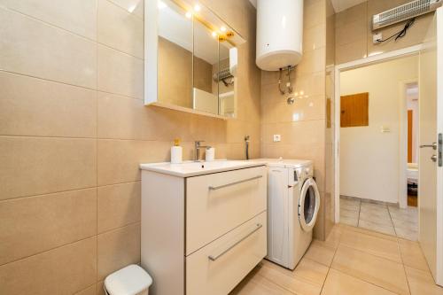 ein Badezimmer mit einer weißen Waschmaschine und einem Trockner in der Unterkunft Apartments Zora in Lun