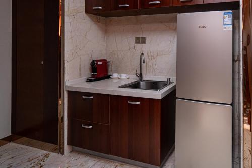 a kitchen with a white refrigerator and a sink at The Grand View Hotel Changzhou in Changzhou