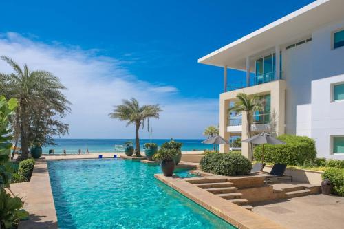 a villa with a swimming pool next to the ocean at Paradox Resort Phuket - SHA Plus in Karon Beach