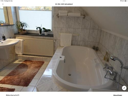 een badkamer met een groot wit bad en een wastafel bij Wohnung mit Whirlpool, Nähe Thülsfelder Talsperre in Cloppenburg