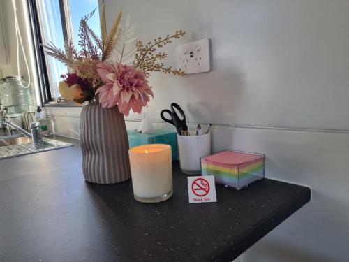 a table with a candle and a vase with flowers and a box at PWL Healing Retreat Accommodation in Rotorua