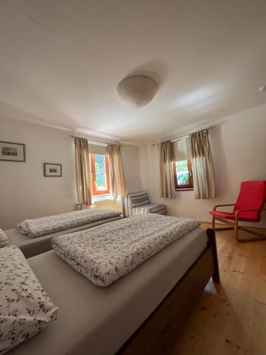 ヘルマゴルにあるFerienwohnung Waldhauserのベッドルーム1室(ベッド2台、赤い椅子付)