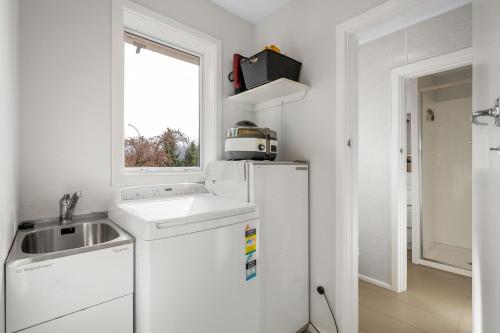 a white kitchen with a sink and a refrigerator at Pops Place - Omarama Holiday Home in Omarama