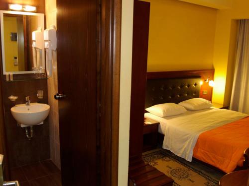 a bathroom with a bed and a sink in a room at Hotel Filoxenia in Chania Town