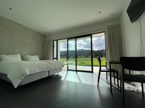 a bedroom with a bed and a table and a window at Woodside Bed and Breakfast in Greytown