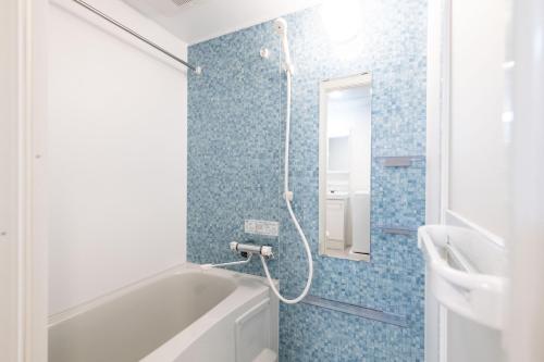 a bathroom with a tub and a shower with blue tiles at Ferio Kamata II in Tokyo