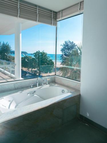 a large bath tub in a bathroom with a large window at Paradox Resort Phuket in Karon Beach