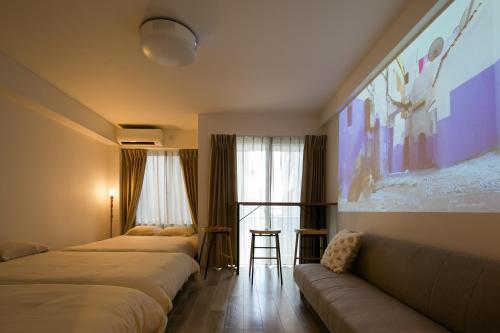 een hotelkamer met 3 bedden en een bank bij trive meieki nishi 106 最大6名宿泊可 名古屋駅まで1駅 太閤通駅徒歩4分 角部屋 無料駐車場付き in Nagoya