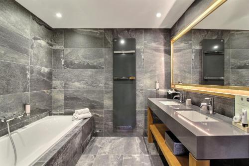 une salle de bain avec deux lavabos et une baignoire dans l'établissement Pure Montagne Resort & Spa, à Saint-Martin-Vésubie