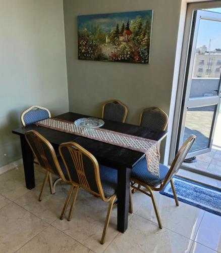 a dining room table with chairs and a painting on the wall at Beautiful 1 bedroom rooftop apartment with a great terrace in Rujm ash Sharāʼirah