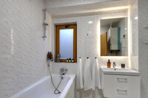a white bathroom with a tub and a sink at Spacious Old Town LOFT for 6 in Bratislava