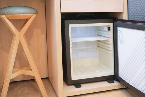 a small refrigerator with its door open next to a stool at Park Central Sakura Hotel in Osaka