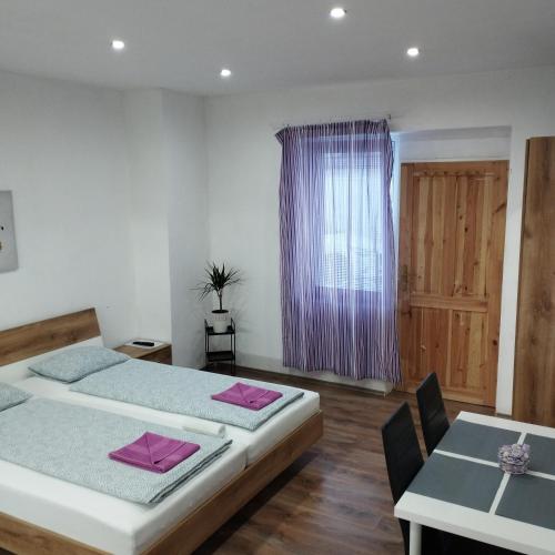 a bedroom with two beds and a table and a window at Apartmány 77 in Veľký Meder