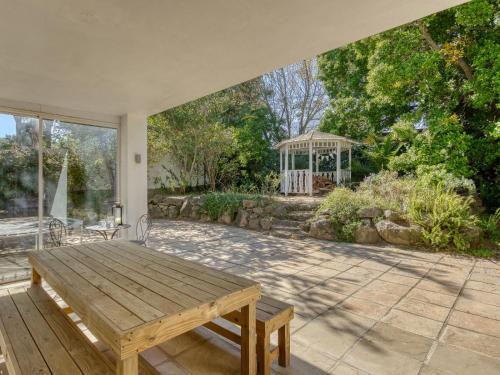 a patio with a wooden table and a gazebo at Explorer Guesthouse in Somerset West